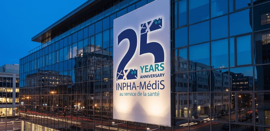 INPHA-MédiS 25 years banner on a glass office building at dusk